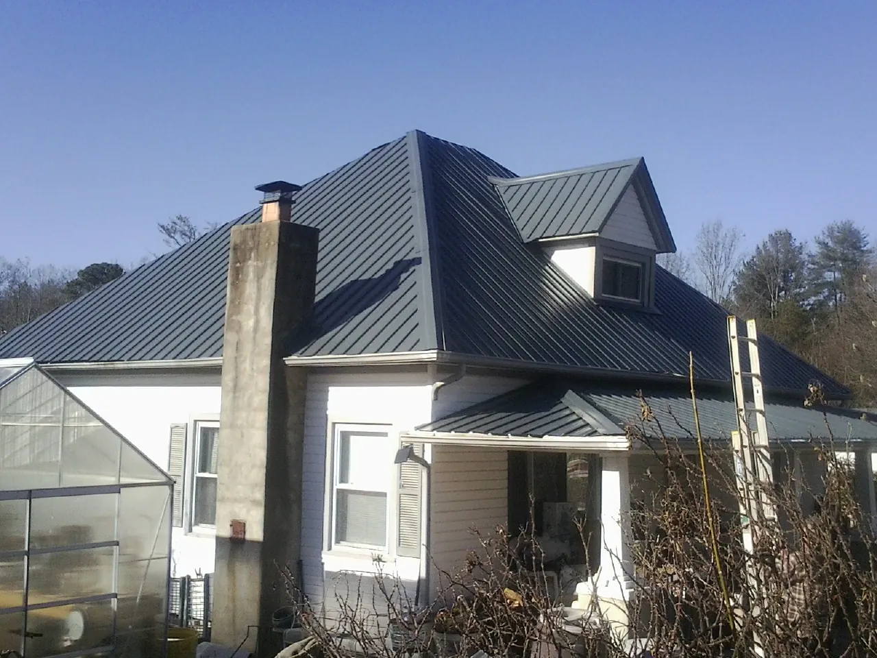 Dark blue standing seam metal roof on a white farmhouse with dormer — Slate & Tile Roof Repair by Roofing Brothers in Fiskeville