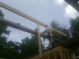 Carpenter setting a ridge beam over a new addition frame — Ice Dam Removal by Roofing Brothers in Fiskeville