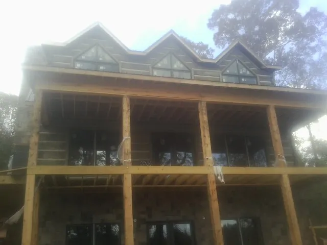 Dormers and porch framing on a large log home under construction — Roof Coating work by our crew in Fiskeville