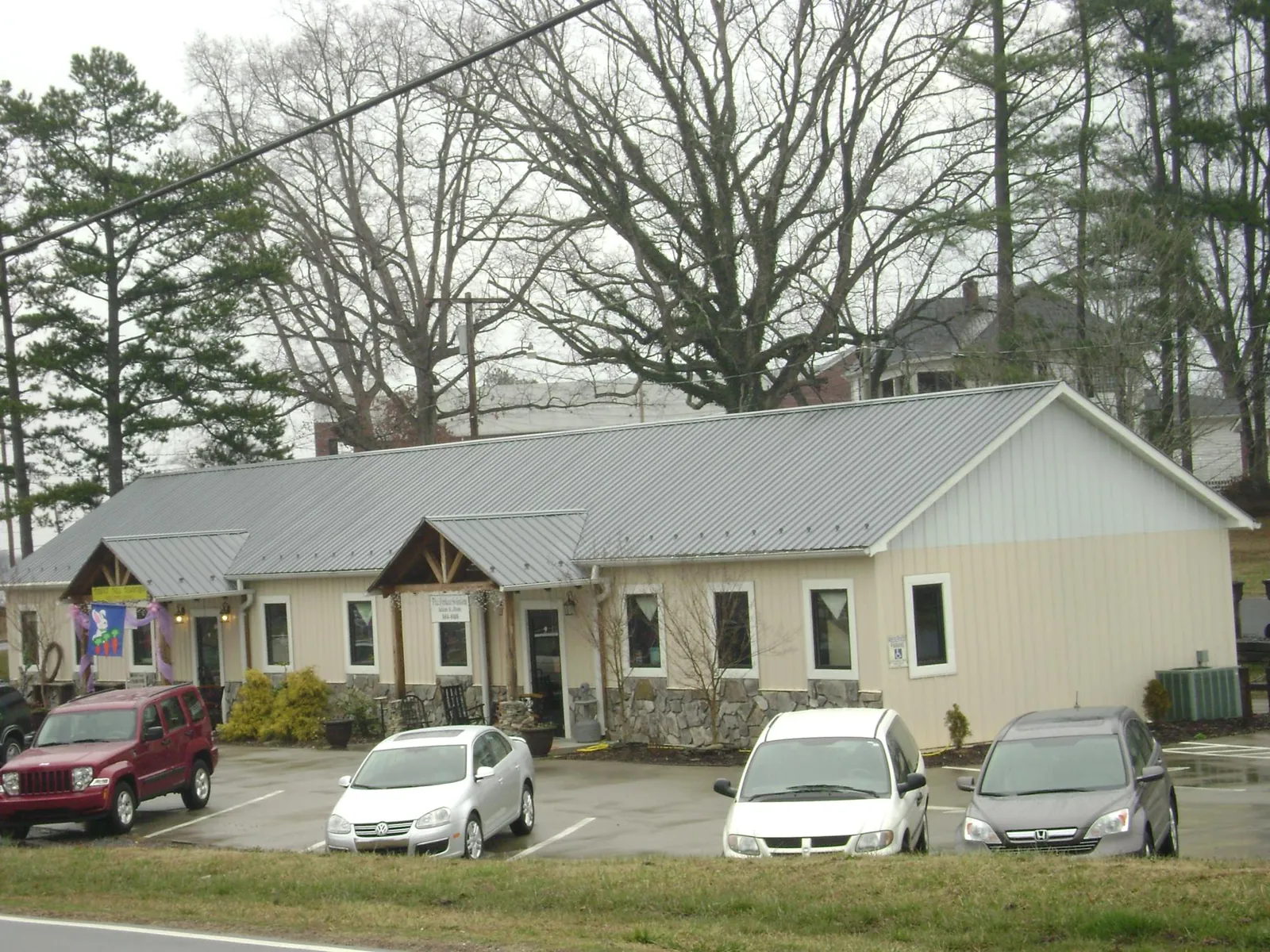 Gray metal roof with timber entry brackets on a small commercial building in Fiskeville