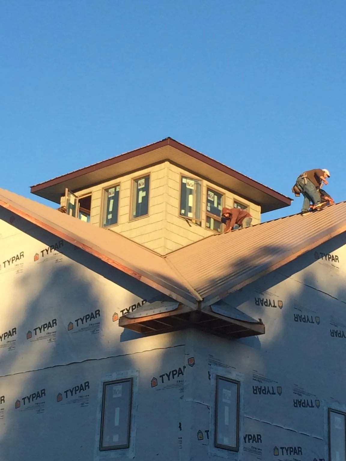 Roofers working around a rooftop cupola on a new metal roof at sunset — Roof Waterproofing in Fiskeville by Roofing Brothers